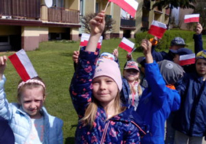 Dzieci na spacerze unoszące w górze flagi.